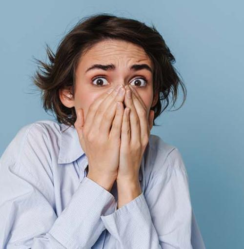 jonge vrouw slaat angstig de handen voor haar mond