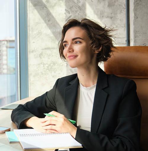 vrouwelijke CEO in stijvol bureau kijkt mijmerend naar buiten