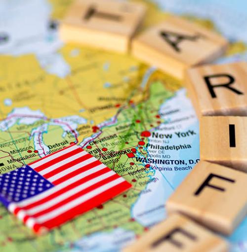 wereldkaart daarop vlag van VS en letterblokjes tariffs