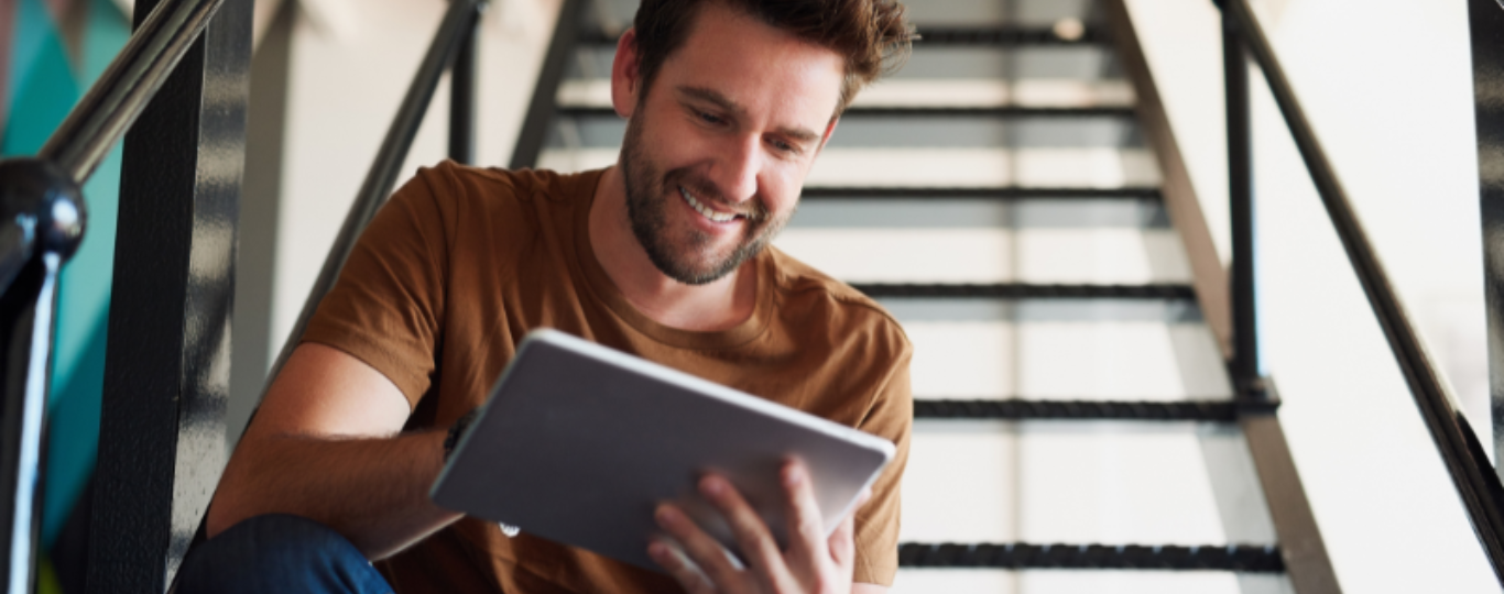 man op trap kijkt op laptop