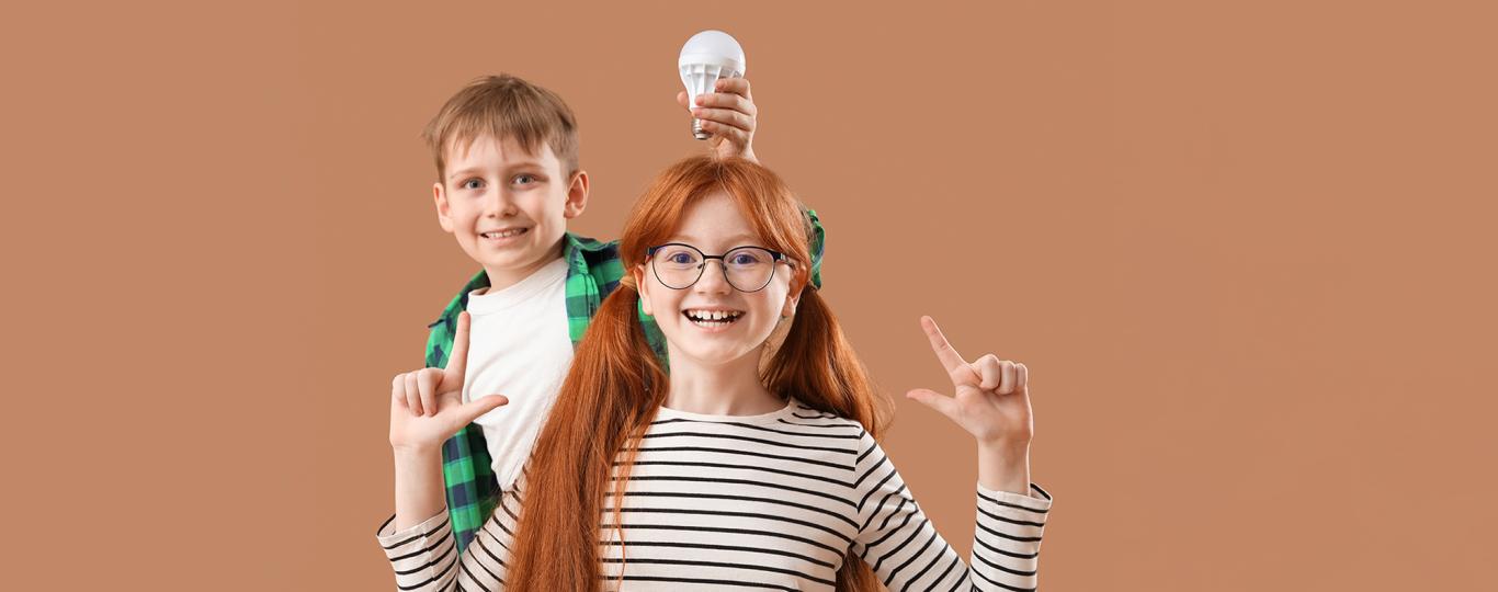 jongen houdt lamp boven het hoofd van zijn zus