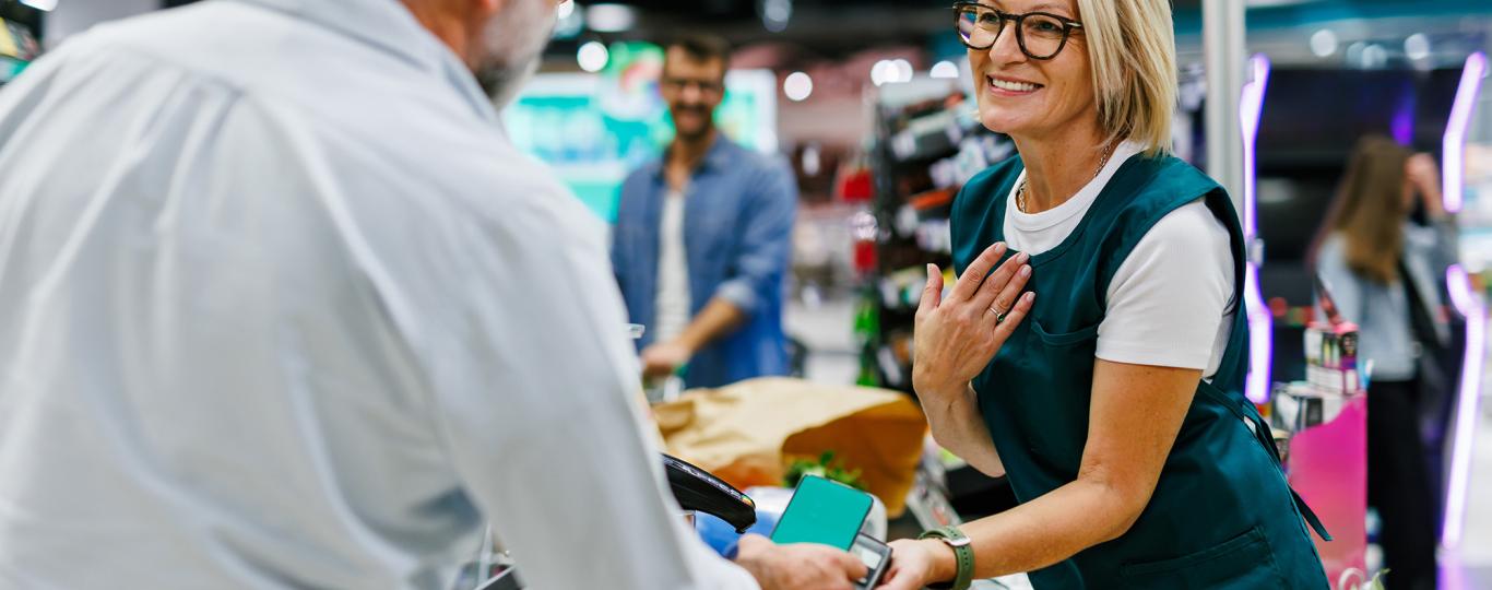 man betaalt via zijn gsm aan een kassierster in de supermarkt