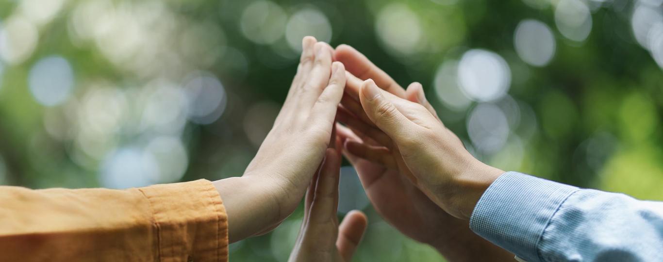 verschillende mensen slagen handen tegen elkaar in de lucht 