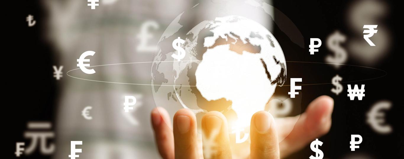 oplichtende kristallen wereldbol met valuta-symbolen in een mensenhand