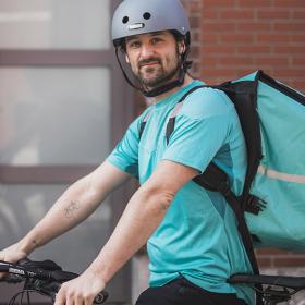 Herman Loos als maaltijdbezorger op fiets