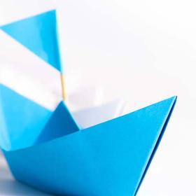 blauw origami bootje wijst de richting