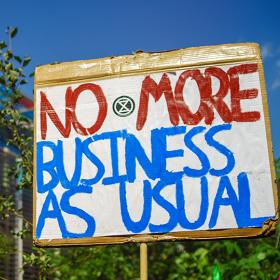 bord met opschrift 'no more business as usual' tijdens klimaatbetoging in Londen