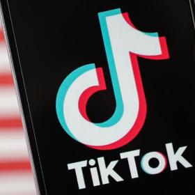 gsm met TikTok-logo, op de achtergrond wazig de Amerikaanse vlag