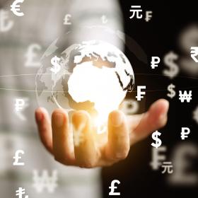 oplichtende kristallen wereldbol met valuta-symbolen in een mensenhand