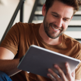 man op trap kijkt op laptop