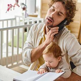 thuiswerkende vader aan de telefoon met peuper op de schoot
