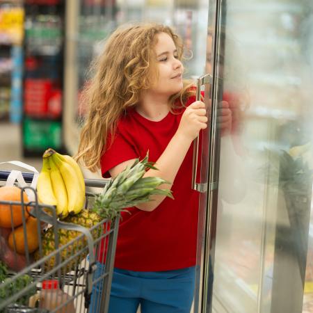 Meisje neemt iets uit een frigo in een supermarkt
