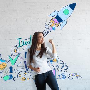 lachende vrouw maakt vuist voor een muur met illustraties die staan voor creatief ondernemerschap