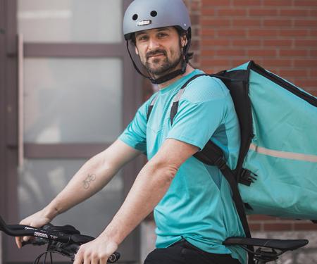 Herman Loos als maaltijdbezorger op fiets