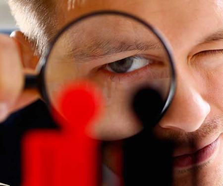 man kijkt door vergrootglas naar mannetjes