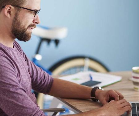 man aan laptop met fiets op de achtergrond