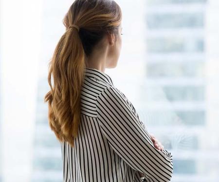 Vrouw kijkt uit raam kantoorgebouw