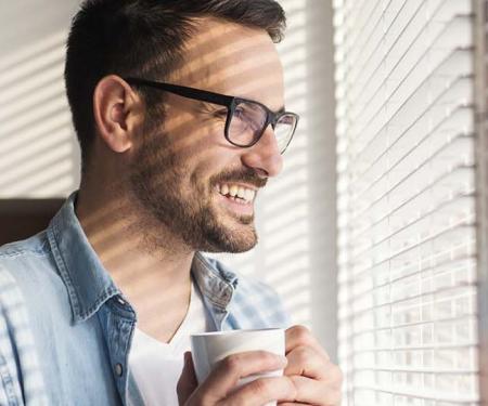 tevreden werknemer met tas koffie in de hand kijkt naar buiten