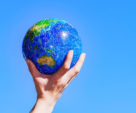 Wereldbol puzzel gedragen op een hand