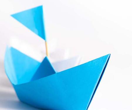 blauw origami bootje wijst de richting