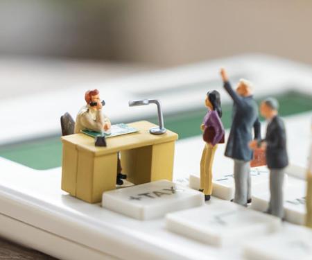 poppetjes schuiven aan voor een bureau aan de knop tax op een rekenmachine