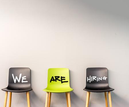 rij lege stoelen met daarop de tekst 'we are hiring'