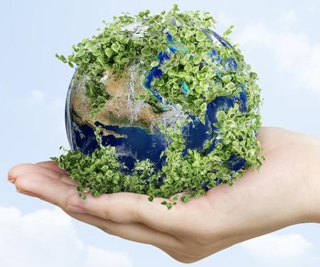 groene wereldbol ligt in zachte hand met rondom een lichtblauwe lucht