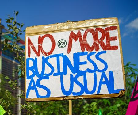 bord met opschrift 'no more business as usual' tijdens klimaatbetoging in Londen