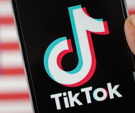 gsm met TikTok-logo, op de achtergrond wazig de Amerikaanse vlag