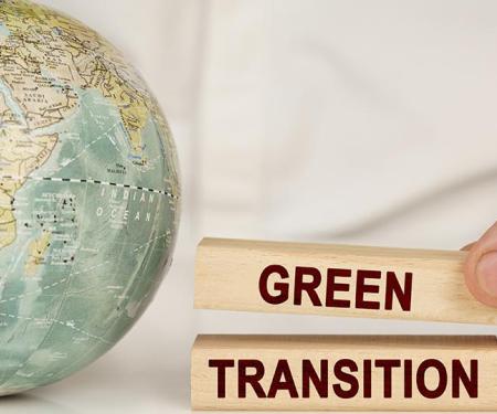 man stapelt blokjes met opschrift green transition naast een wereldbol