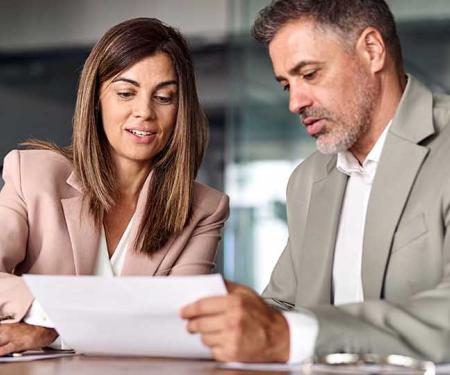 man en vrouw in bedrijfsomgeving bekijken samen een document