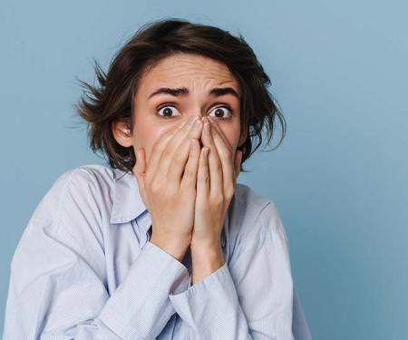 jonge vrouw slaat angstig de handen voor haar mond