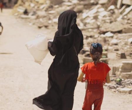 vrouw en meisje wandelen weg langs puin in Gaza stad