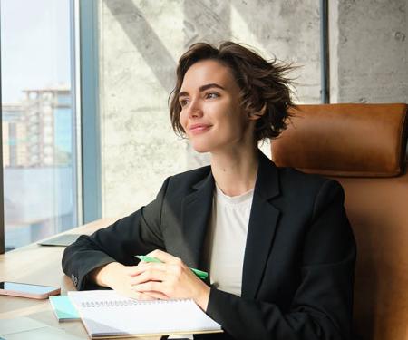 vrouwelijke CEO in stijvol bureau kijkt mijmerend naar buiten