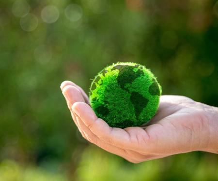grassige wereldbol in een mensenhand op een natuurlijke achtergrond